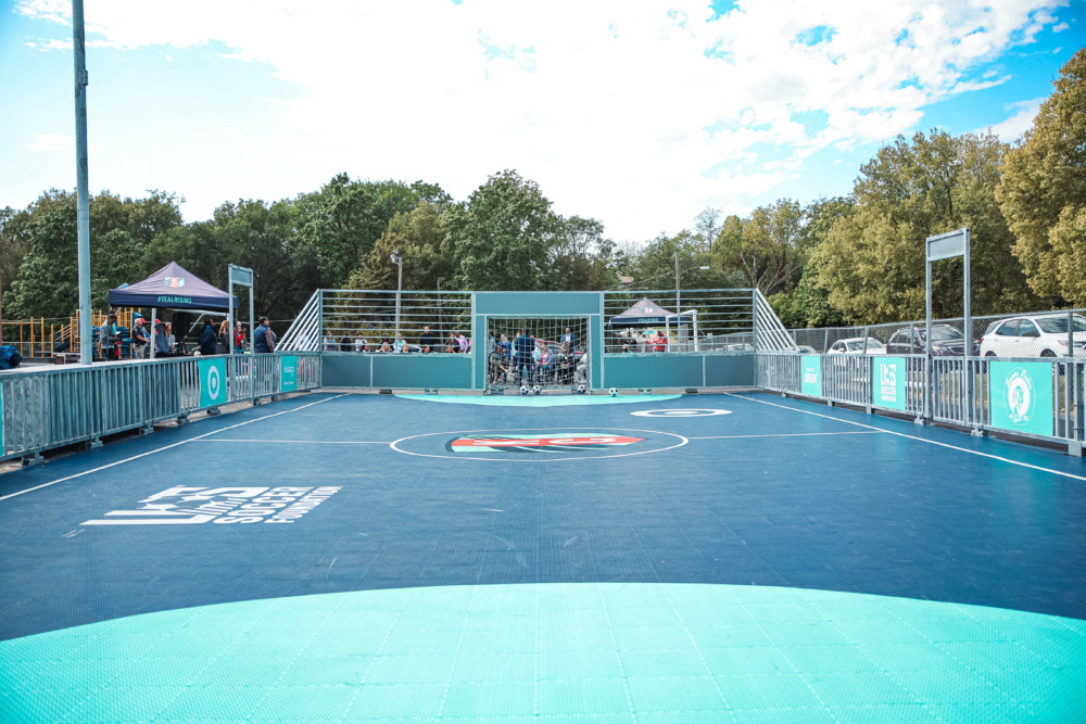 A teal and blue mini-pitch with the KC Current logo in the center circle.